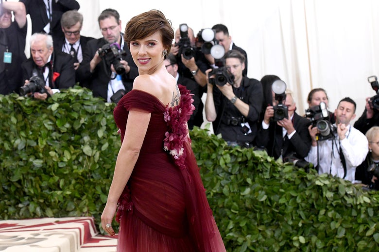 Scarlett Johansson in a maroon dress, looking back over her shoulder.